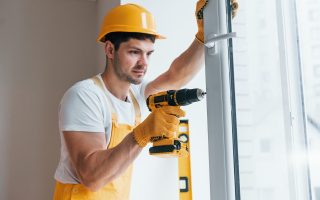 handyman-in-yellow-uniform-installs-new-window-by-using-automatic-screwdriver.jpg